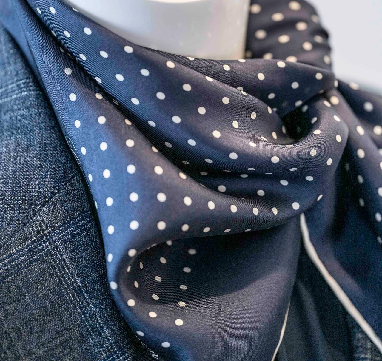 Photo of a navy silk scarf with white dots and a jacket.